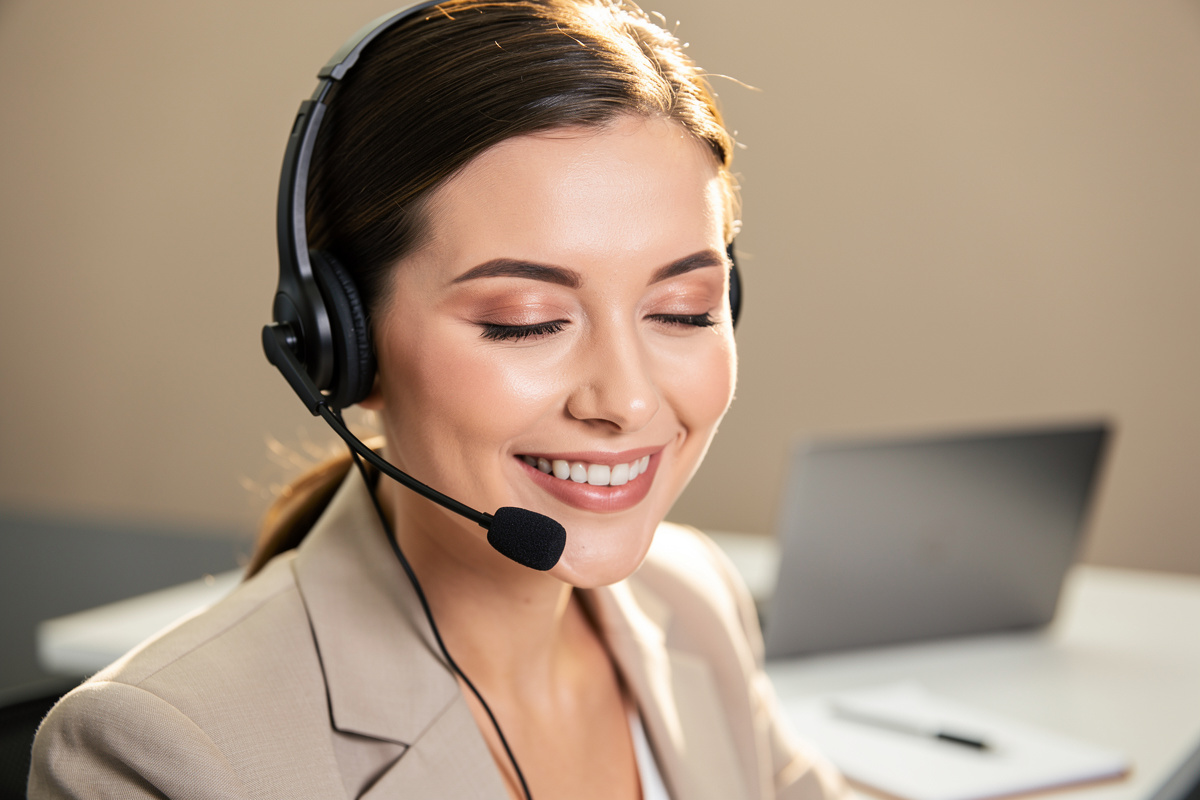 Secrétaire souriante au téléphone illustrant un accueil téléphonique professionnel et chaleureux en auto-école